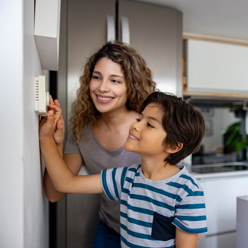 mother and son changing temperature on thermostat