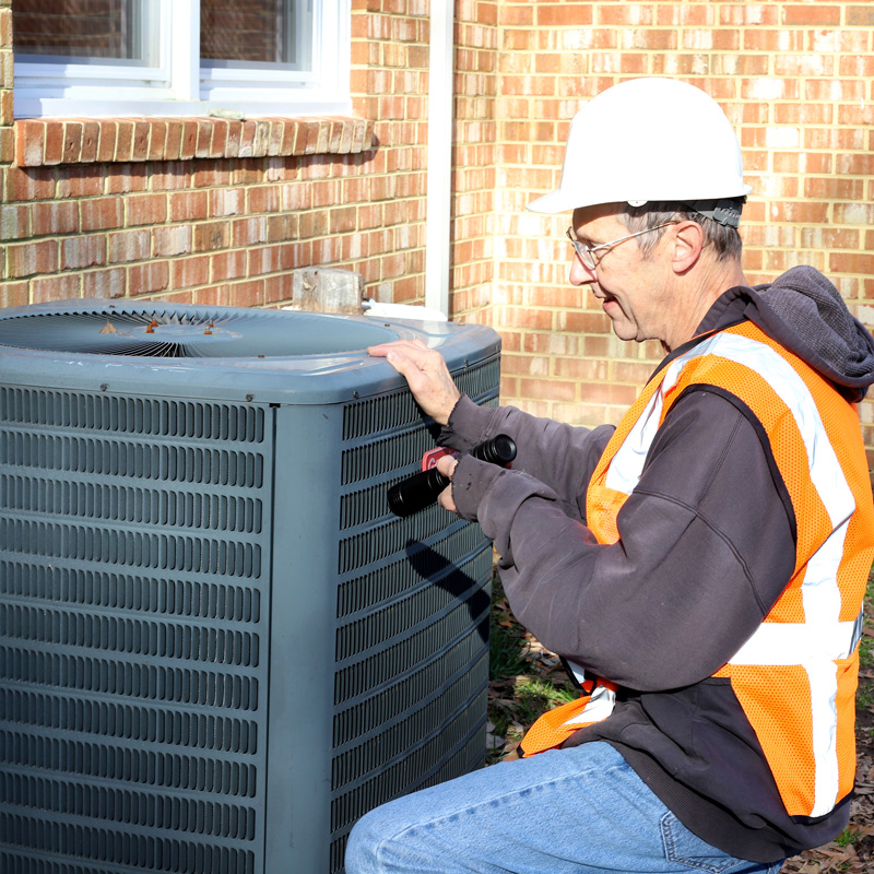 repair man looking at ac unit