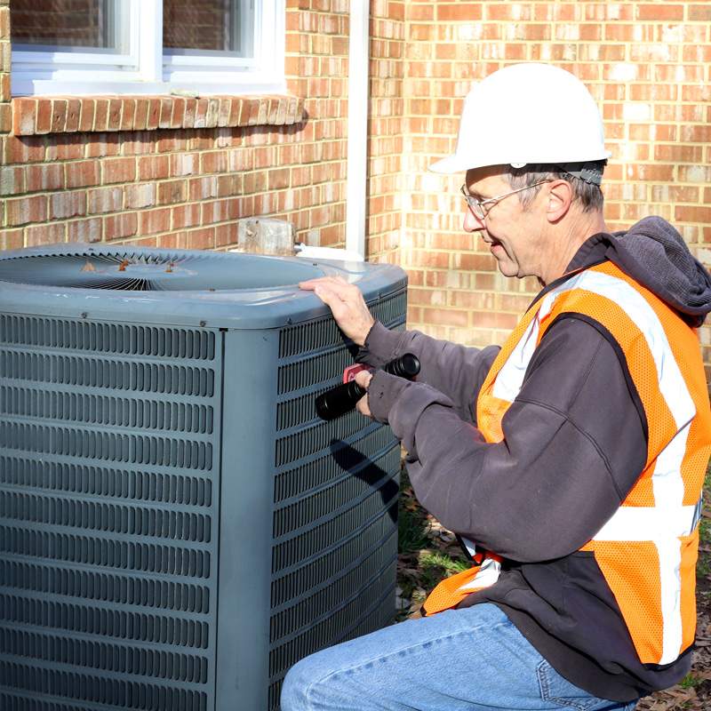 HVAC technician inspecting outdoor AC condenser in Seattle & Ballard AC service